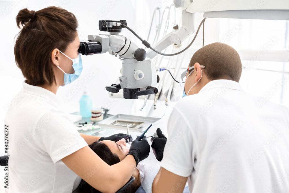 Difficult cases in stomatology. Back view of two dentists making treatment in modern dental office Difficult cases in stomatology. Back view of two dentists making treatment in modern dental office