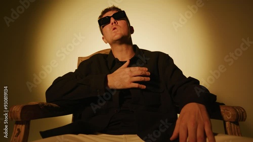 Rap artist singing in a chair for a music video on a warm background