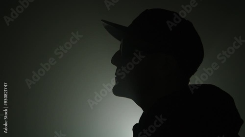 Silhouette of a rap artist singing for a music video on a dark background
