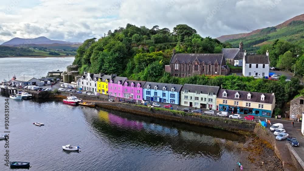 Aerial view of Portree town with colourful houses and fishing boats in Scotland. Scenic view of the natural harbour and port by high ground and cliffs. Popular tourist destination on the Isle of Skye. Aerial view of Portree town with colourful houses and fishing boats in Scotland. Scenic view of the natural harbour and port by high ground and cliffs. Popular tourist destination on the Isle of Skye.
