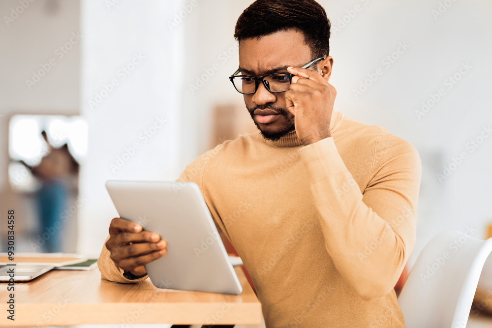 Reading News. Pensive black businessman in glasses using tablet checking his mail or schedule, free space Reading News. Pensive black businessman in glasses using tablet checking his mail or schedule, free space