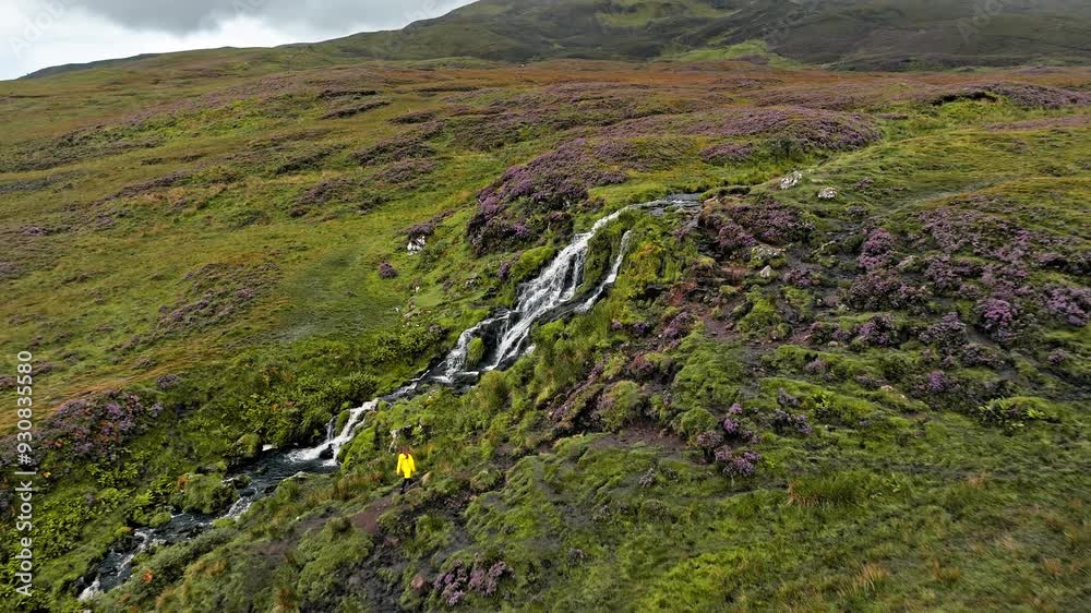 Aerial view of a tourist enjoying the Scottish highlands falls in Scotland. Scenic drone view of a happy woman visiting the waterfalls on the Island of Skye. Aerial view of a tourist enjoying the Scottish highlands falls in Scotland. Scenic drone view of a happy woman visiting the waterfalls on the Island of Skye.