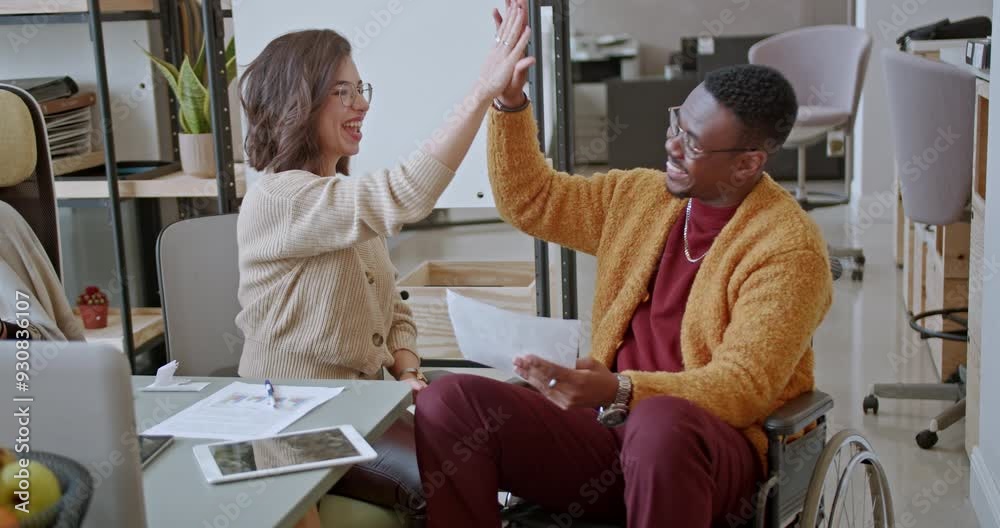 In a joyful moment, two colleagues give each other a high five in the office, representing teamwork and shared achievement, fostering a positive work environment.