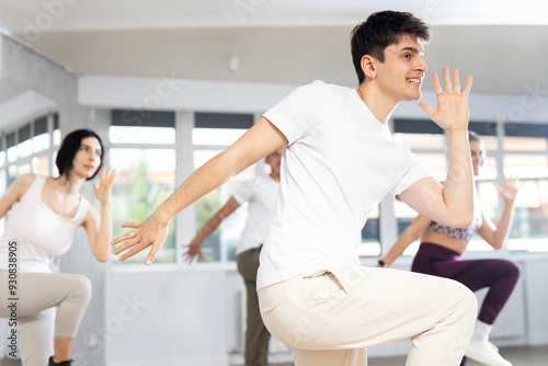 Group of young people, girls and guys in sportive casual style clothes dancing in choreography class photo