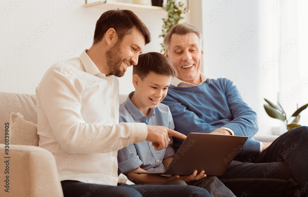 Boy Using Laptop Sitting Between Father And Grandpa Doing Homework Online On Sofa At Home. Selective Focus Boy Using Laptop Sitting Between Father And Grandpa Doing Homework Online On Sofa At Home. Selective Focus