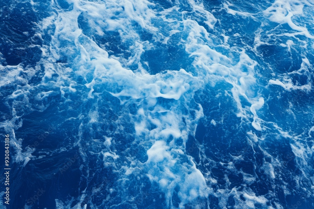 Fototapeta premium Top view of blue ocean water with intricate wave textures and water splashes, creating an abstract background of the sea surface, showcasing the dynamic movement and vibrant blue tones of the ocean.