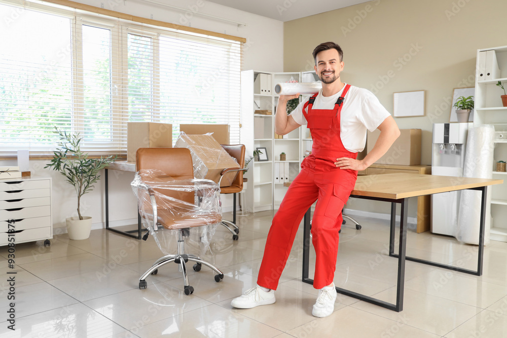 Male worker with roll of stretch film in office Male worker with roll of stretch film in office