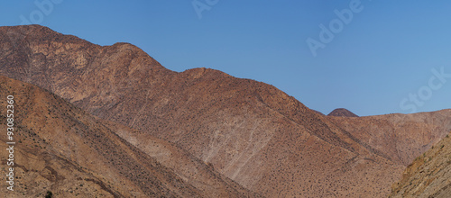 A picturesque mountain range under a clear blue sky without clouds, emphasizing the stark, rugged beauty and the peaceful isolation of the natural landscape. photo