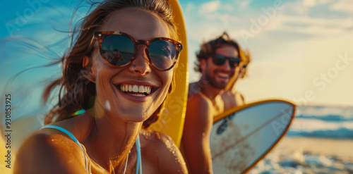 Young adults enjoy a sunny beach day with surfboards while smiling and relaxing by the ocean in the late afternoon