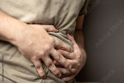 A close-up image of a person clutching their stomach, indicating severe abdominal pain or discomfort. The image vividly portrays the physical symptoms associated with conditions like gastritis, indige photo