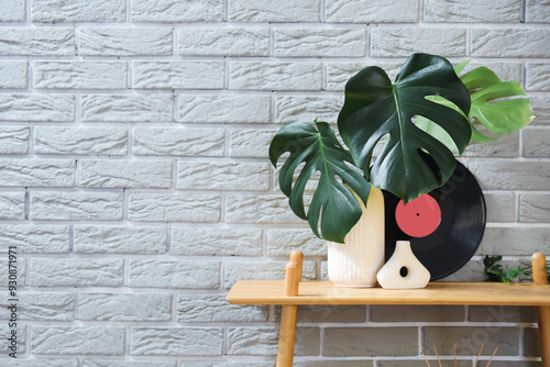 Vase with palm leaves and vinyl disk on shelf near grey brick wall photo