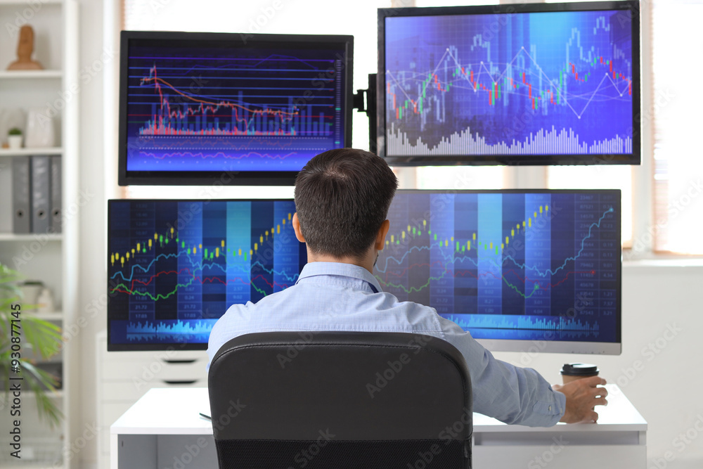 Male trader working at table in office, back view