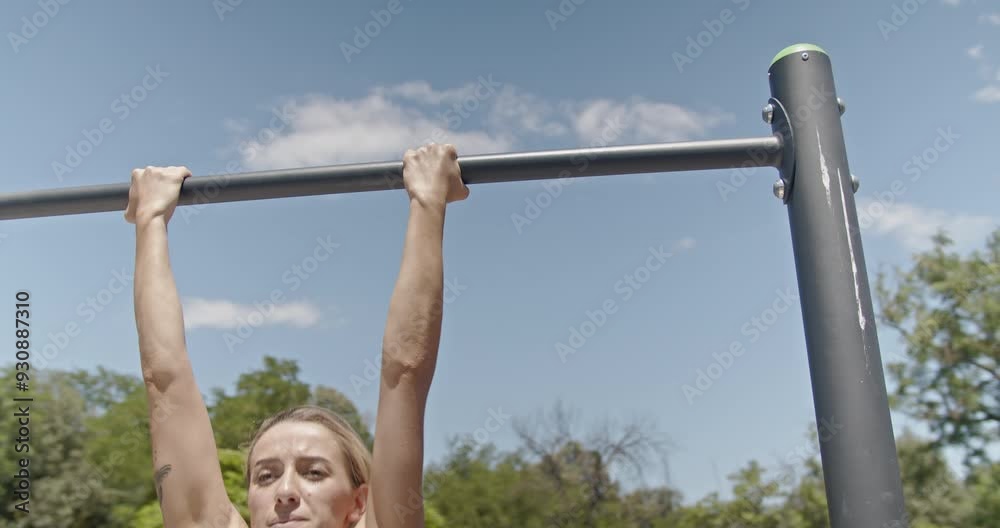 Gorgeous fit woman engages in pull-ups in a sunny park, emphasizing her dedication to strength training, fitness, and outdoor workouts.