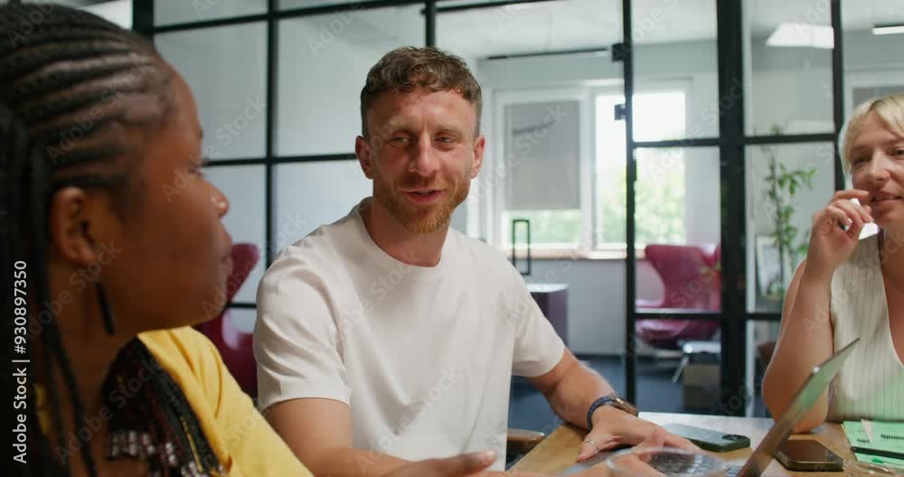 A group of young people are smiling and talking while sitting in an office meeting. Business planning, startup A group of young people are smiling and talking while sitting in an office meeting. Business planning, startup