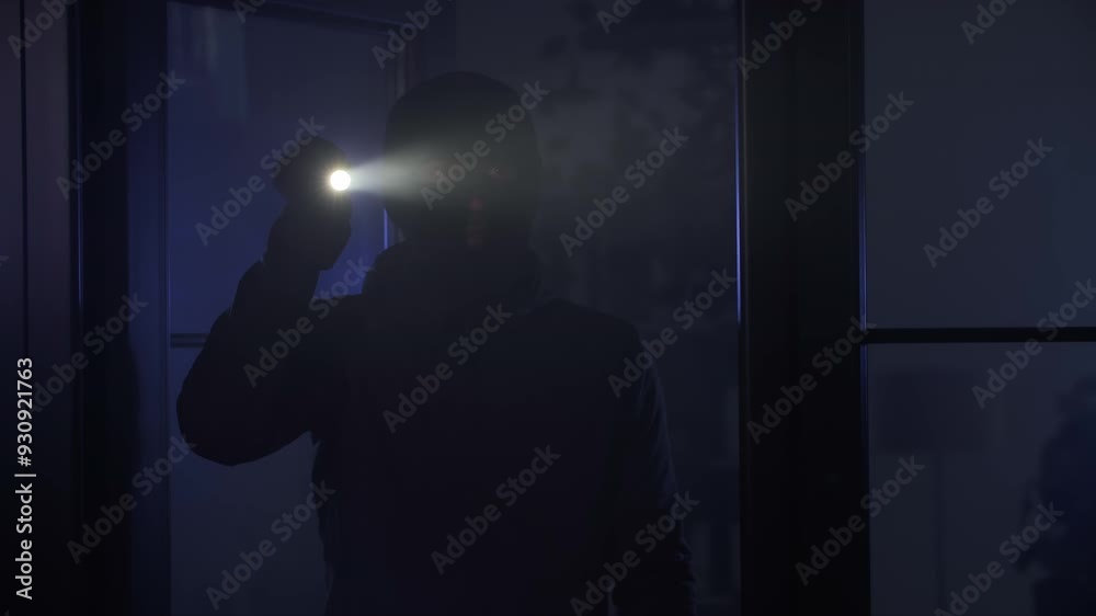 illegal entry into an apartment, man in balaclava with flashlight in his hands sneaks into room at night illegal entry into an apartment, man in balaclava with flashlight in his hands sneaks into room at night