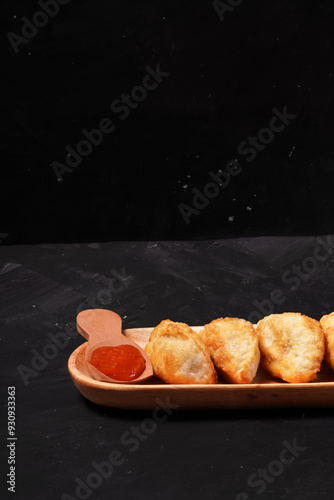 Fried stuffed Cireng, a traditional Indonesian snack filled with seasoned beef fat or jando, perfect with chili sauce dip, photographed against a dark background. photo