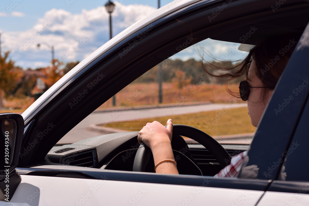 Looking through a car window young woman driving on a sunny autumn day Looking through a car window young woman driving on a sunny autumn day