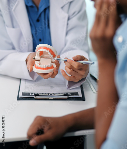 Dentist consultation - patient visit at the dental clinic office. Female dentist wearing dentures to explain teeth Recommend guidelines for orthodontics Dentist giving advice on patient's condition