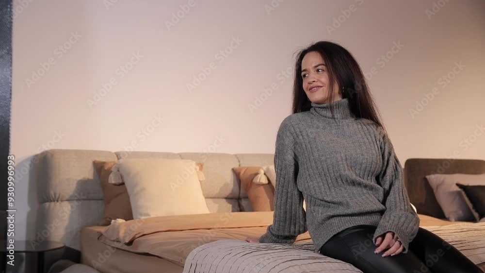 A smiling woman is sitting and choosing a bed for her bedroom in a modern furniture store. A smiling woman is sitting and choosing a bed for her bedroom in a modern furniture store.