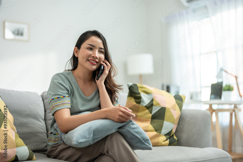 Asian beautiful woman sit on sofa and talk on mobile phone in house. Asian beautiful woman sit on sofa and talk on mobile phone in house.