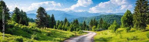 Scenic view of a winding road through lush green landscape with mountains, trees, and a bright blue sky.