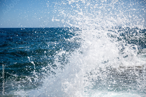 Waves splashing on rocks in the sea on a sunny day.