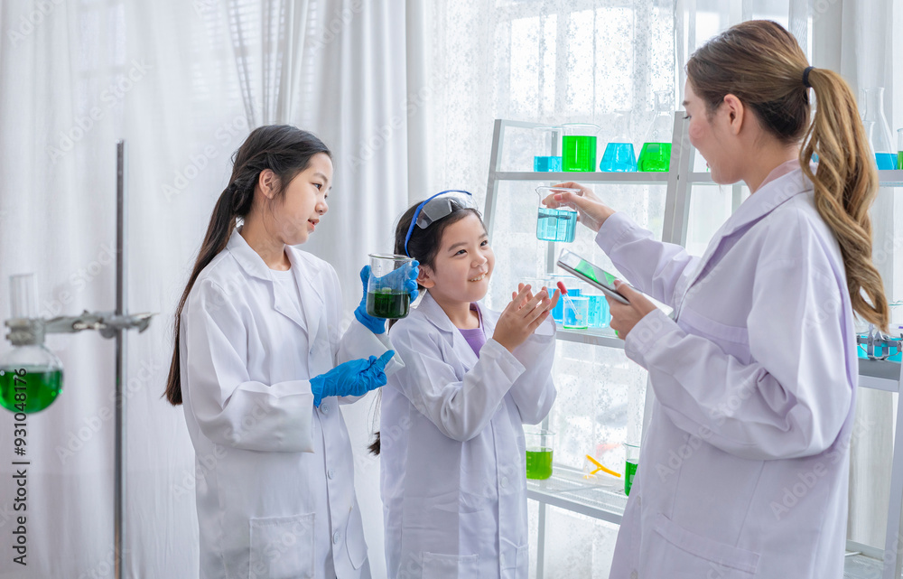 cheerful kids studying science in chemical laboratory,female scientist as a mentor is teaching the student cheerful kids studying science in chemical laboratory,female scientist as a mentor is teaching the student