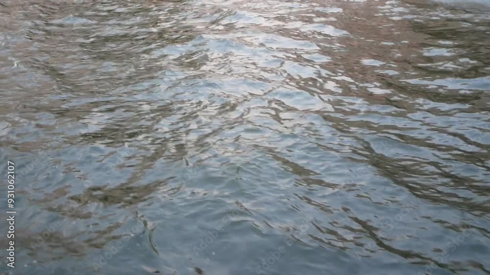 texture of water surface in river in bright sunny sparkles on surface withwaves in morning light waves break ashore on a tropical river with warm-colored reflection. texture of water surface in river in bright sunny sparkles on surface withwaves in morning light waves break ashore on a tropical river with warm-colored reflection.