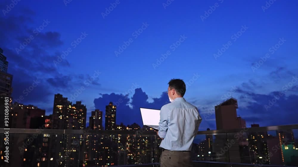 Young asian businessman with laptop on the building rooftop at city night Young asian businessman with laptop on the building rooftop at city night