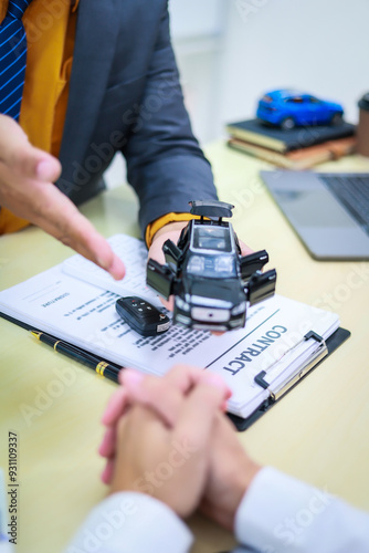 A businessman is working at his desk, focused on car financing, car sales, and insurance. He is analyzing customer data related to automobile financing and crafting strategies to improve sales photo