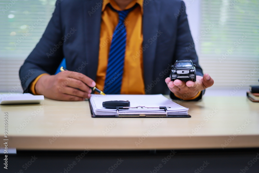 Fototapeta premium A businessman is working at his desk, focused on car financing, car sales, and insurance. He is analyzing customer data related to automobile financing and crafting strategies to improve sales
