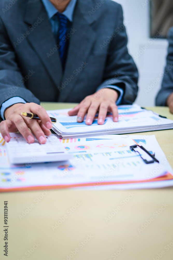 Two businessmen are seated at a desk in an office, engaged in a meeting focused on analysis, finance, and marketing strategies, with documents and graphs spread across the table. Two businessmen are seated at a desk in an office, engaged in a meeting focused on analysis, finance, and marketing strategies, with documents and graphs spread across the table.