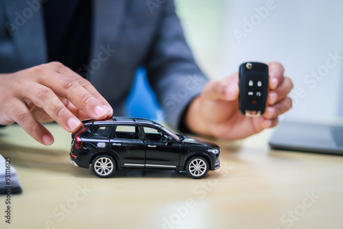 A businessman is working at his desk, focused on car financing, car sales, and insurance. He is analyzing customer data related to automobile financing and crafting strategies to improve sales