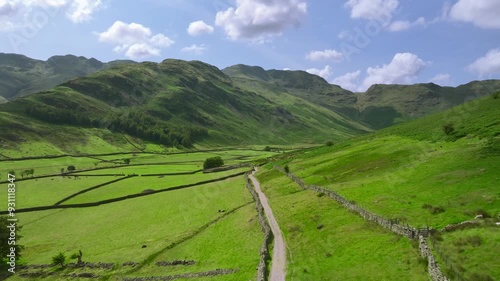 Flying over and along valley path with surrounding mountains. Mickleden, The Langdales, Lake District, UK photo