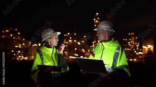 Team Engineer working at night shift with laptop Inside Oil Refinery Gas Chemical plant. Senior Engineer wearing safety jacket and PPE working about Petrochemica Chemical Prodiction  photo