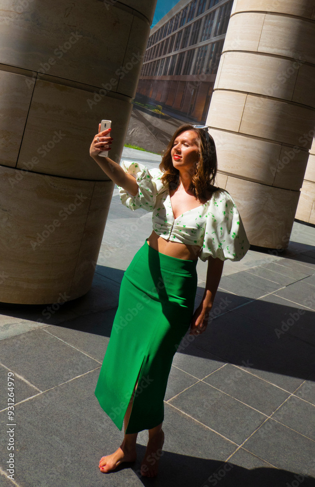 Joyful young caucasian woman winks, bites her tongue, takes selfie on phone. Blonde model wears hat in sunny weather. Positive emotions concept. High quality photo