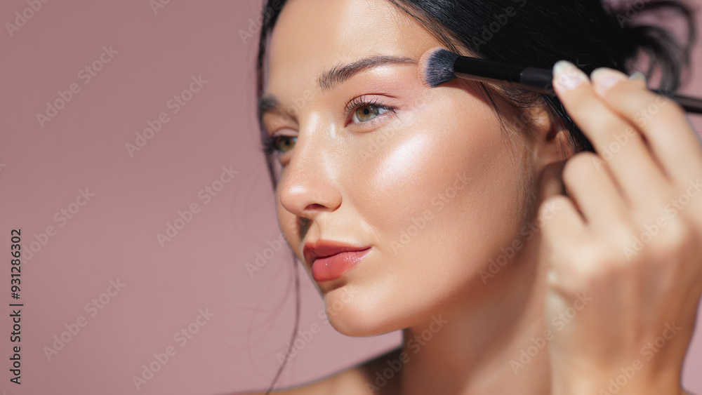 Model Applying Shimmering Highlighter on Cheekbone with Makeup Brush Model Applying Shimmering Highlighter on Cheekbone with Makeup Brush