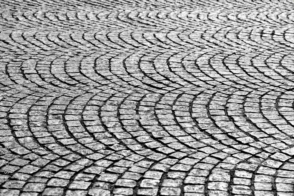 Old cobblestones on a street of “Montmartre“ in Paris, France. Shiny historic basalt ashlars and blocks reflecting sunshine. Pavement pattern in curves and arcs, black and white with high contrast. Old cobblestones on a street of “Montmartre“ in Paris, France. Shiny historic basalt ashlars and blocks reflecting sunshine. Pavement pattern in curves and arcs, black and white with high contrast.