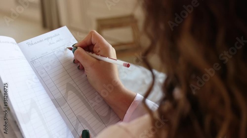 A beautiful curly-haired girl in a pink silk pajamas lies on the bed, relaxed. A middle-aged woman is getting ready for bed in the morning, smiling. Girl read her notebook, write some notes