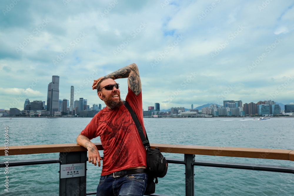 A tourist enjoys the scenic view from the Hong Kong waterfront with the skyline in the background A tourist enjoys the scenic view from the Hong Kong waterfront with the skyline in the background