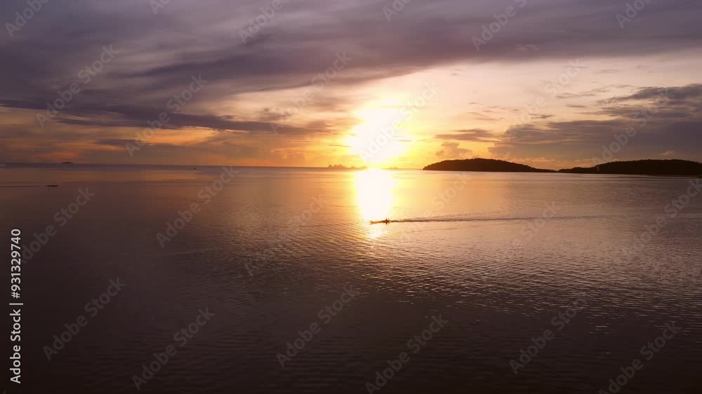 Aerial view of a lone Thai longtail boat sailing in the tropical sea of Thailand against a morning sunrise sky. Aerial view of a lone Thai longtail boat sailing in the tropical sea of Thailand against a morning sunrise sky.