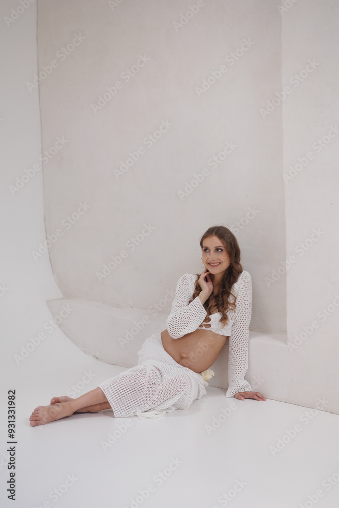 Beautiful pregnant woman in white separate dress with rope in hands. Big pregnant belly. Pretty woman smile, waiting child. Light play on woman's body and face Beautiful pregnant woman in white separate dress with rope in hands. Big pregnant belly. Pretty woman smile, waiting child. Light play on woman's body and face