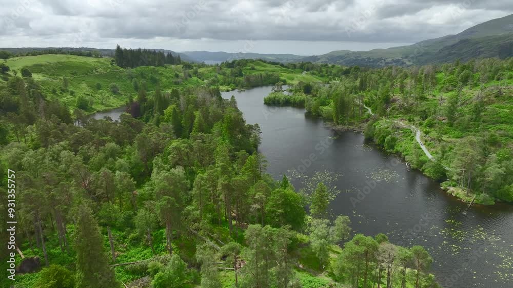 Secluded lake surrounded by trees with drone rise showing wider countryside and Coniston Water. Tarn Hows, Lake District National Park, Cumbria, UK Secluded lake surrounded by trees with drone rise showing wider countryside and Coniston Water. Tarn Hows, Lake District National Park, Cumbria, UK