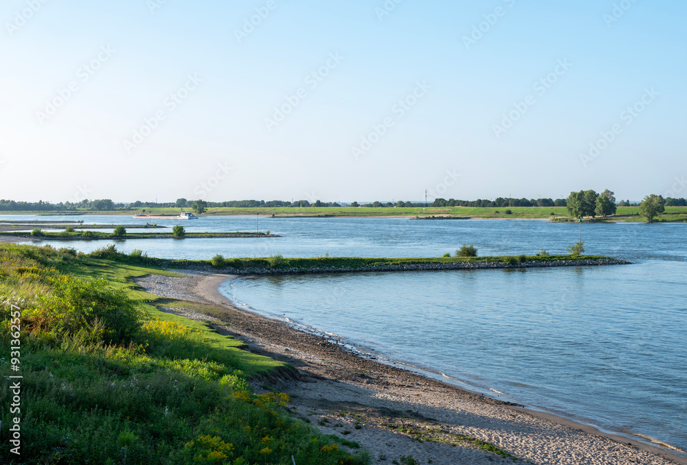 evening sun on bank of river waal near nijmegen with passing ships