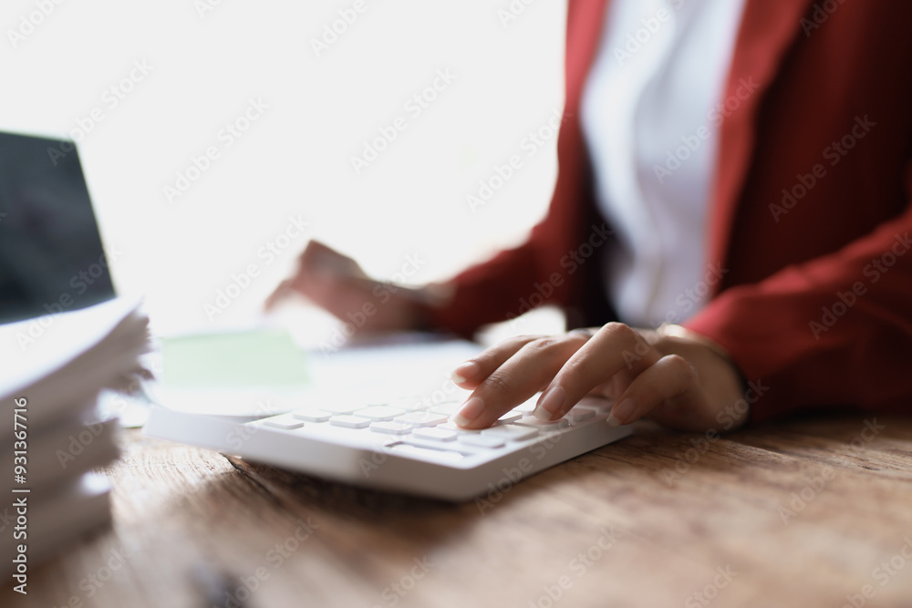 woman meticulously plans a finance audit, using a computer and calculator to review budget documents and ensure accuracy woman meticulously plans a finance audit, using a computer and calculator to review budget documents and ensure accuracy