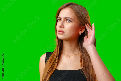 Young Woman Listening Intently Against a Green Screen photo