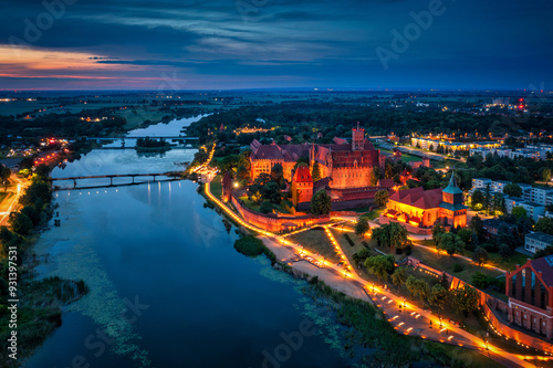 Castle of theTeutonic Order in Malbork by the Nogat river at dusk.