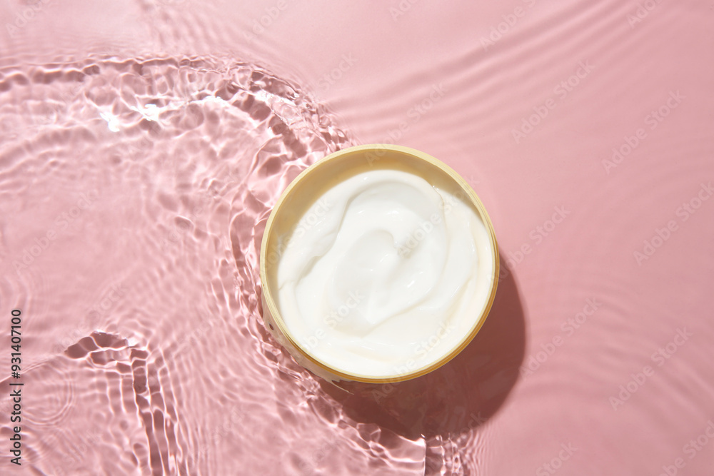 Cosmetic product. Jar with cream in water on pink background, top view Cosmetic product. Jar with cream in water on pink background, top view