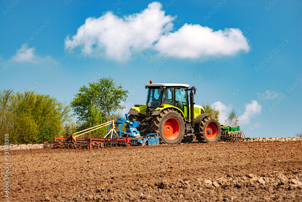 Fototapeta premium Tractor with harrow and cultivator on the field during tillage