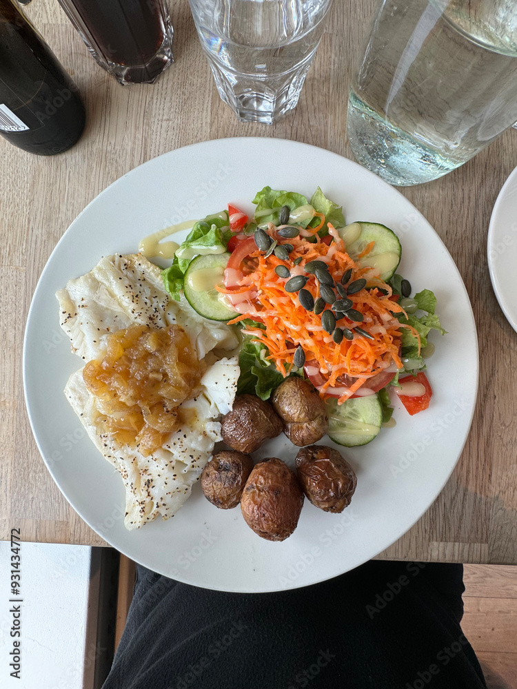 Reykjavik, Iceland - fresh steamed cod fish dish served with green salad, potatoes and a house onion sauce Reykjavik, Iceland - fresh steamed cod fish dish served with green salad, potatoes and a house onion sauce